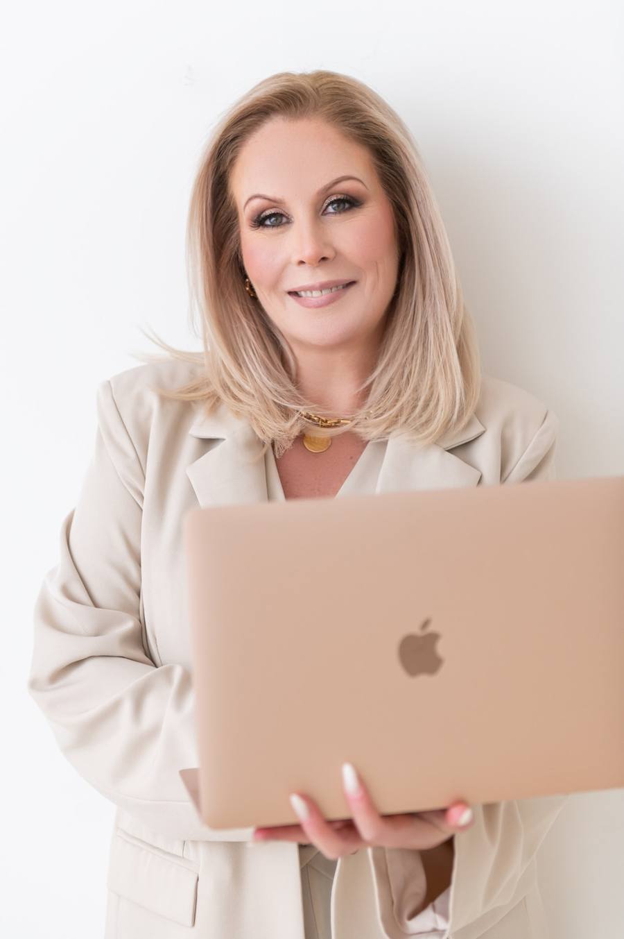 Dawn McGruer in a cream blazer holding a gold laptop