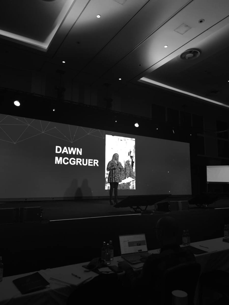 Dawn McGruer speaking on stage at a business event.