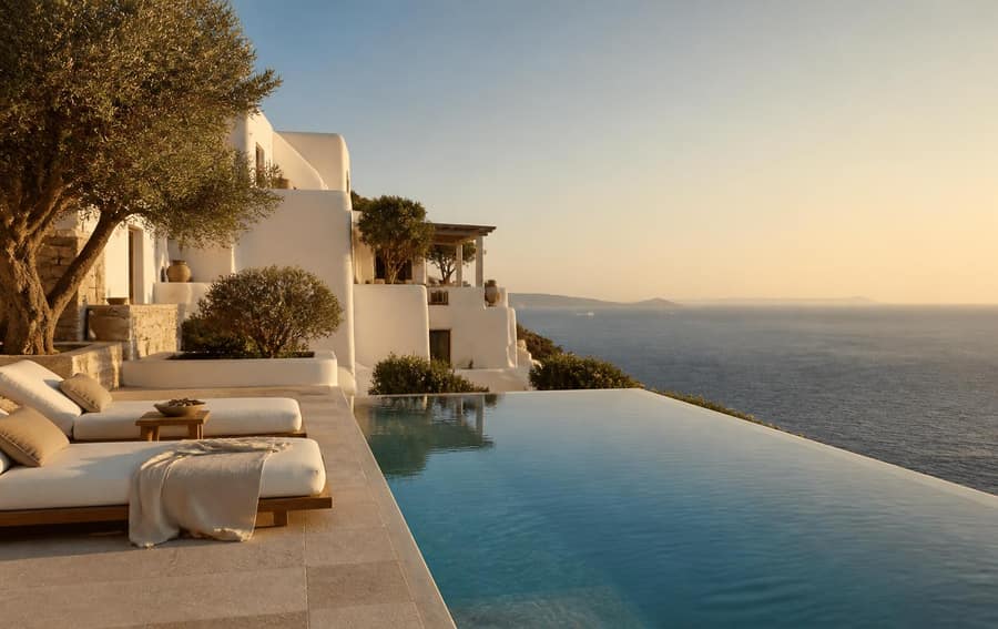 Whitewashed cliffside villa with infinity pool overlooking the Aegean sea at golden hour